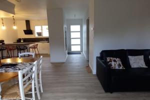 ein Wohnzimmer mit einer schwarzen Couch und einer Küche in der Unterkunft Villa d'Orée, Bordeaux Saint-Aubin-de-Médoc in Saint-Aubin-de-Médoc + 6 Fotos