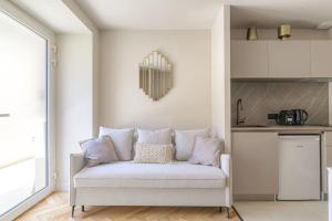 a white couch in a room with a kitchen at Studio with sleeping area for 4, Saint-Didier in Saint-Didier-au-Mont-dʼOr