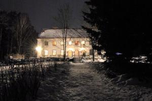 Lesogorskaya estate RUUSYAVI في Lesogorskiy: منزل كبير في الليل مع ثلج على الأرض