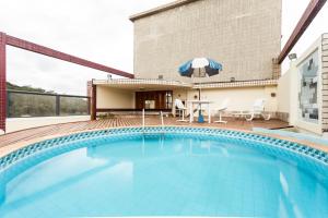 una piscina con tavolo e ombrellone in un edificio di Hotel Lopes Caxambu a Caxambu