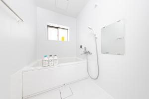 a white bathroom with a shower and a sink at Kosumosu in Tokyo