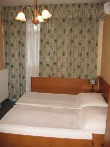 Schlafzimmer mit einem großen weißen Bett und einem Fenster in der Unterkunft Hotel Arnold in Tata