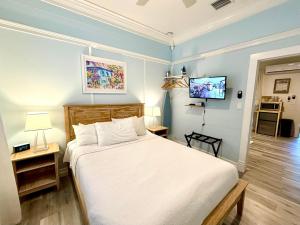 een slaapkamer met een wit bed en een televisie bij Atocha Cottage - Harbor Walk Hideaways in Key West