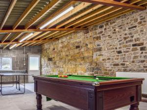 a room with a pool table and a brick wall at May Cottage-Uk38279 in Cloughton