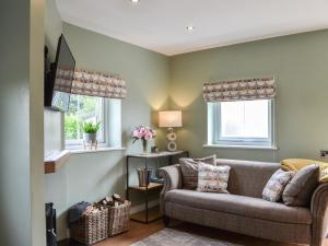 a living room with a couch and two windows at The Hen House - Uk38436 in Kilham