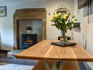 a vase of yellow flowers sitting on a wooden table at Johnsons Cottage - Uk39727 in Taddington