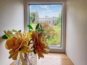 a vase with flowers in front of a window at Johnsons Cottage - Uk39727 in Taddington