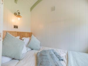 a bedroom with a bed with white sheets and blue pillows at The Wensleydale - Uk40152 in Rathmell +10 photos