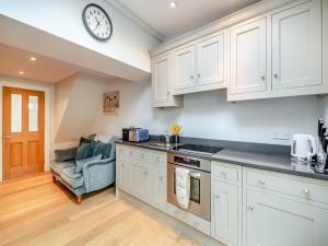 a kitchen with white cabinets and a clock on the wall at Ryburn House - Uk43518 in Thornton Dale +23 photos