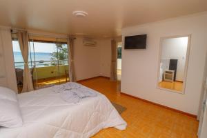 a bedroom with a white bed and a large window at Pousada Praia da Lagoinha in Bombinhas