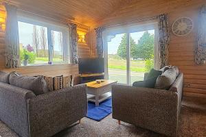 a living room with two couches and a tv at Heather Lodge with Hot Tub in Holcombe Burnell