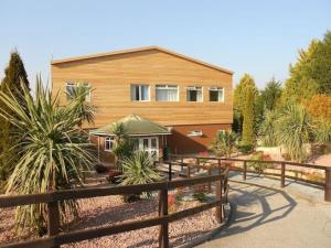a wooden house with a fence in front of it at Heather Lodge with Hot Tub in Holcombe Burnell