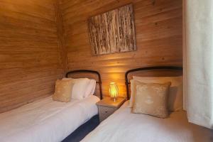 two beds in a room with wooden walls at Heather Lodge with Hot Tub in Holcombe Burnell