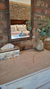 a mirror and a table with a vase on it at Lentelus-Greeff Cottage in Oudtshoorn +18 photos
