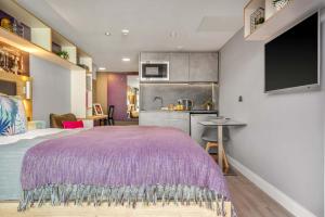 a bedroom with a purple bed and a kitchen at Practical Studio For 2 In Leeds with Free Grab&Go Breakfast in Headingley