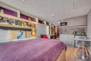 a bedroom with a purple bed and a kitchen at Practical Studio For 2 In Leeds with Free Grab&Go Breakfast in Headingley