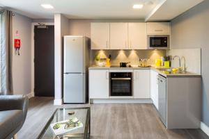 a kitchen with white cabinets and a white refrigerator at Comfortable Studio For 2 In Leeds with Free Grab&Go Breakfast in Headingley