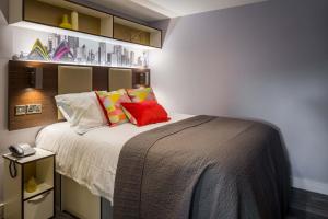 a bedroom with a large bed with colorful pillows at Comfortable Studio For 2 In Leeds with Free Grab&Go Breakfast in Headingley +4 photos