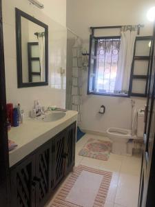 ein Badezimmer mit Waschbecken und Toilette und einem Fenster in der Unterkunft Hibiscus in Mambrui in Mambrui