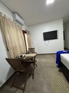 Zimmer mit einem Tisch, einem TV und einem Bett in der Unterkunft Casa vista mar a 20 metros da praia de garça torta em Maceio in Maceió