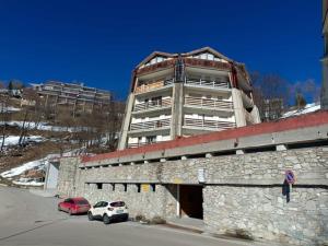 Dos coches aparcados delante de un gran edificio. en La Piramide sulle piste, en Prato Nevoso