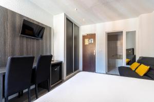 a room with a bed and a table with chairs at Hotel de la Baie in Bandol