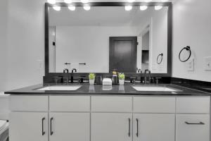 a bathroom with two sinks and a large mirror at Industrial Loft Living 2BR 2BA in Greenville +34 photos