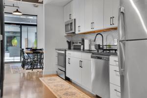 a kitchen with white cabinets and a stainless steel refrigerator at Industrial Loft Living 2BR 2BA in Greenville