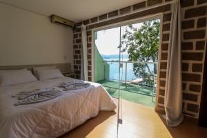a bedroom with a bed and a large glass window at Pousada Praia da Lagoinha in Bombinhas +108 photos