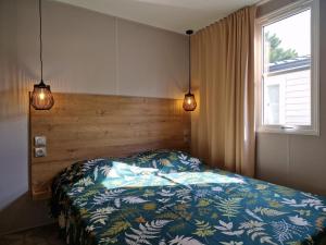 ein Schlafzimmer mit einem Bett und einem Fenster und zwei Lichtern in der Unterkunft Camping Del Mar 52, Mobile Home Excellence, 3 chambres, 6 personnes, bord de mer in Argelès-sur-Mer