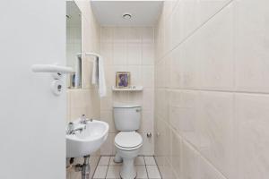 a white bathroom with a toilet and a sink at Odeon Towers 1102 in Strand +30 photos