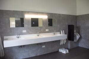 a bathroom with two sinks and two mirrors at Camping POD 3 persoons Lindershoeve Bergeijk in Bergeijk