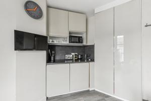 a kitchen with white cabinets and a clock on the wall at Studio Mac Mahon - Champs Elysees in Paris
