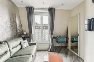 a living room with a couch and a large window at Studio Mac Mahon - Champs Elysees in Paris