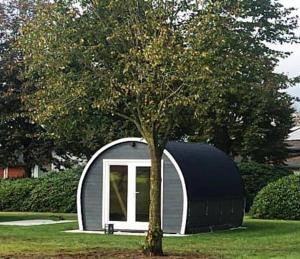 a small black and white shed with a tree at Camping POD 3 persoons Lindershoeve Bergeijk in Bergeijk