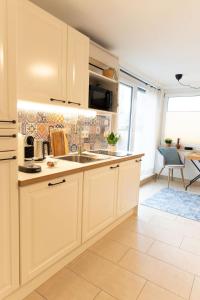 een keuken met witte kasten en een spoelbak bij Würzburg Studio mit Dachterrasse - Tiefgarage & Nähe Bahnhof in Würzburg