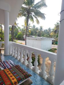 a balcony with a white railing and palm trees at Emma Homestay in Pattiyūrgrāmam