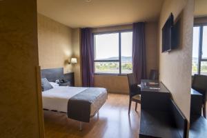 ein Hotelzimmer mit Bett, Schreibtisch und Fenster in der Unterkunft Alda El Espinar in El Espinar
