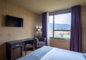 ein Hotelzimmer mit Bett, Schreibtisch und Fenster in der Unterkunft Alda El Espinar in El Espinar