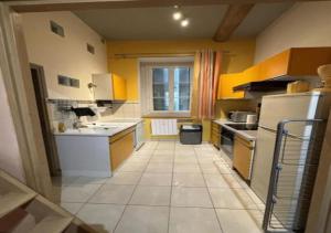 La cuisine est équipée de placards jaunes et d'un réfrigérateur blanc. dans l'établissement Appartement au centre de Tarare, à Tarare
