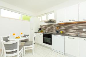 a kitchen with white cabinets and a table and chairs at Apartment Summer Chill 1 in Trsteno