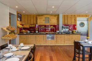 a kitchen with wooden cabinets and a table with chairs at Hotel Le Stella in Châtel