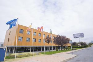 Un hotel con banderas frente a un edificio. en Alda El Espinar, en El Espinar