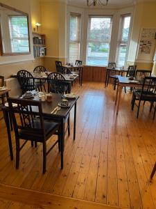 a dining room with tables and chairs and windows at An Caislean Corratavey Guest House in Ballycastle