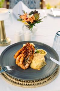 a plate of food with a fish on a table at Kisiwa on the Beach in Paje
