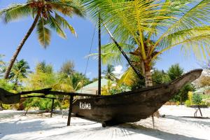 a boat on the beach with two palm trees at Kisiwa on the Beach in Paje