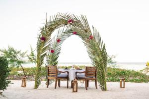 a table with chairs under an arch on the beach at Kisiwa on the Beach in Paje