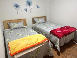 SMiguel, 1P Grande dpto, 4 camas, wifi, lavadora terraza في ليما: سريرين في غرفة بها زهور زرقاء على الحائط