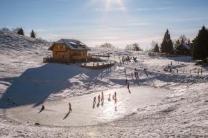grupa ludzi bawiących się w śniegu w pobliżu domku w obiekcie Apartments Krvavec w mieście Cerklje na Gorenjskem