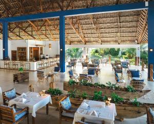 a restaurant with tables and chairs in a room at Kisiwa on the Beach in Paje